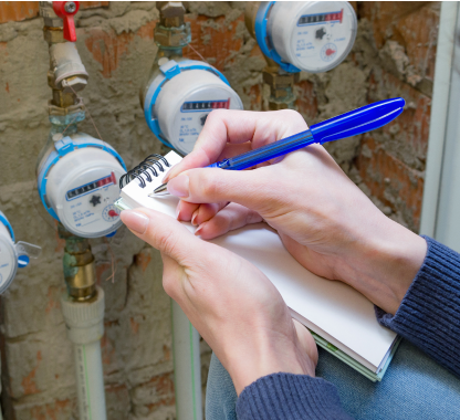 Person writing in a notebook by a water meter